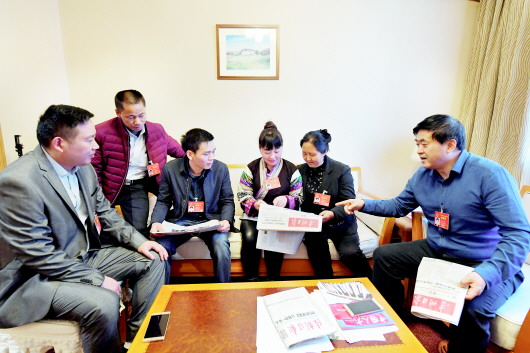 会议间隙,代表们利用报刊了解“两会”新闻。