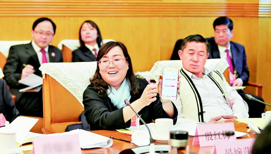 3月13日,贵州代表团分组审议“两高”工作报告,殷红梅代表在发言时用手机二维码展示她的“2018检察印迹”。  贵州日报当代融媒体记者　张丽　摄
