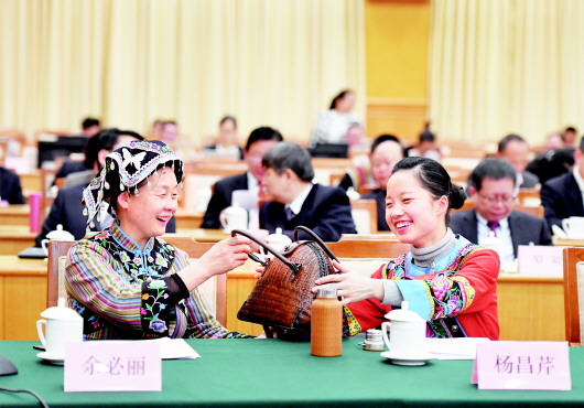 一场会议结束后,全国人大代表余必丽与杨昌芹交流赤水竹编提包工艺和民族工艺品市场前景。