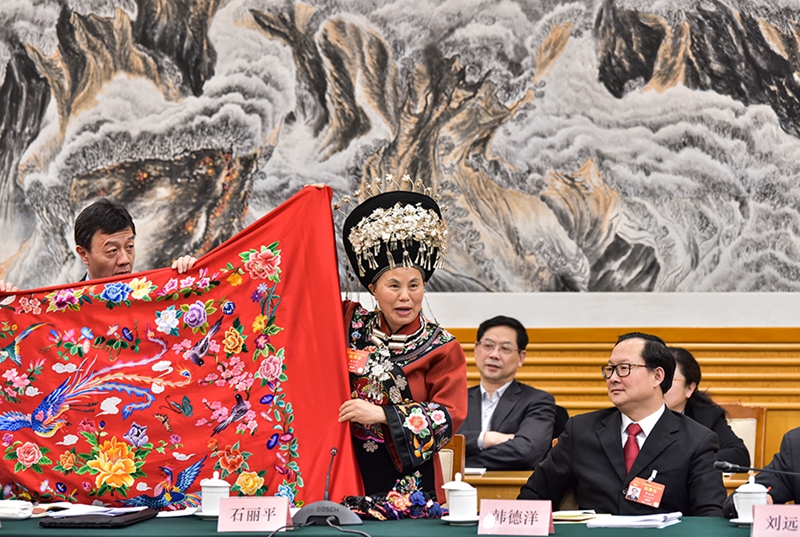 3月7日，石丽平代表在十三届全国人大二次会议贵州代表团全体会议上发言时展示当代易地扶贫搬迁群众绣娘的作品